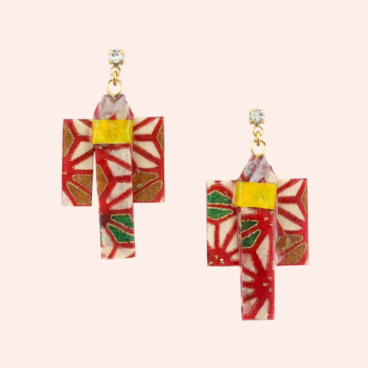 Pair of earrings with red and white geometric design on a beige background