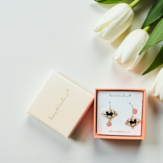 Earrings in a pink box with white tulips on a light background