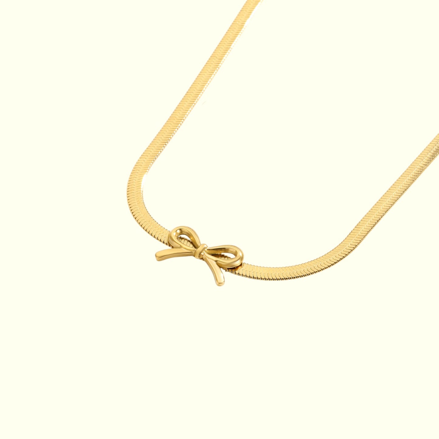 Gold necklace with a bow pendant on a white background
