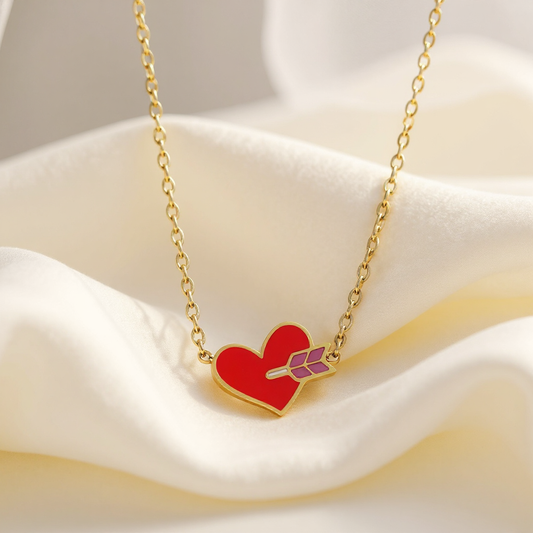 Necklace with a red heart pendant and gold chain on a white fabric background