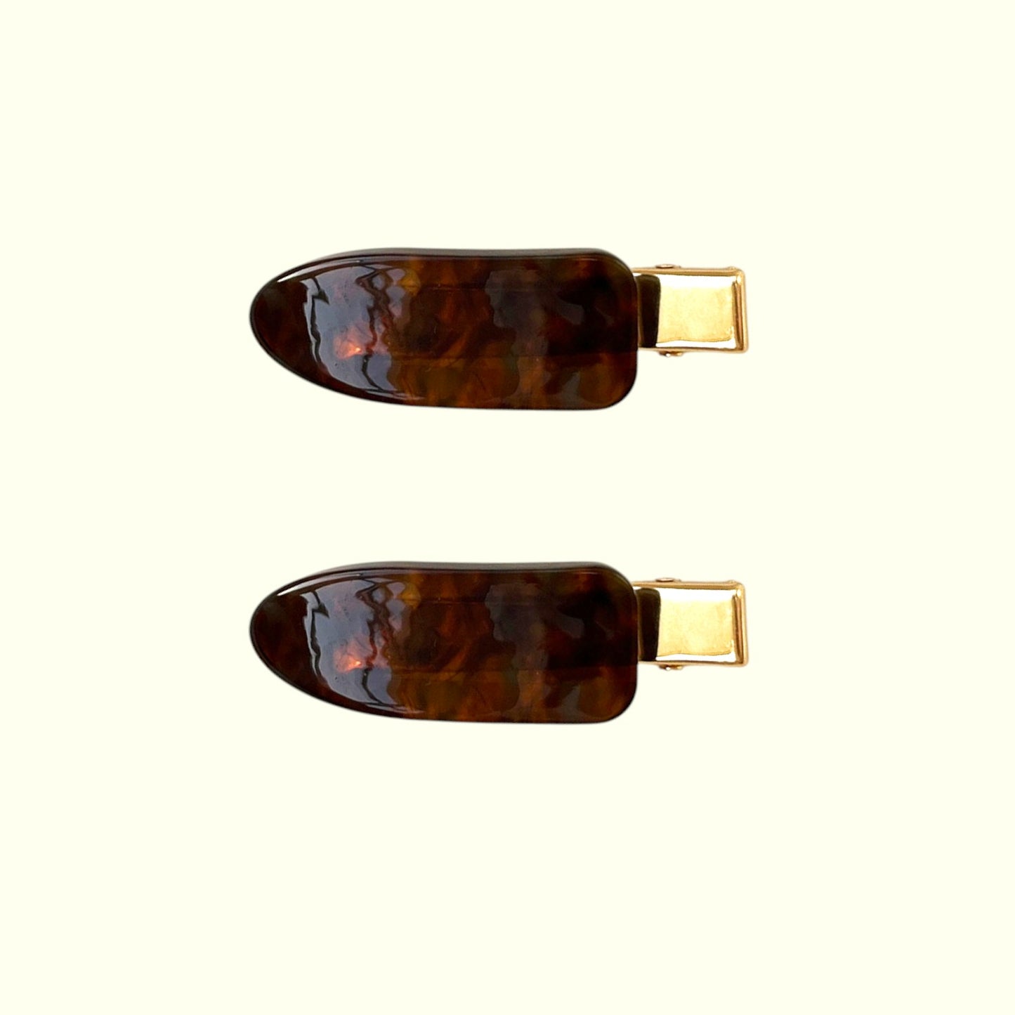 Two tortoiseshell hair clips with gold hardware on a white background