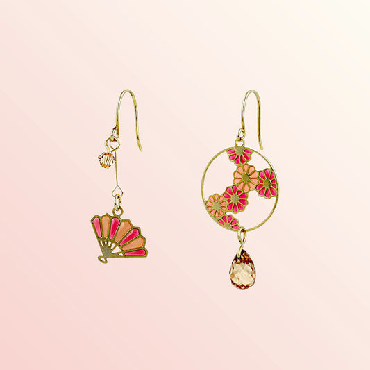 Pair of gold earrings with floral designs on a pink background