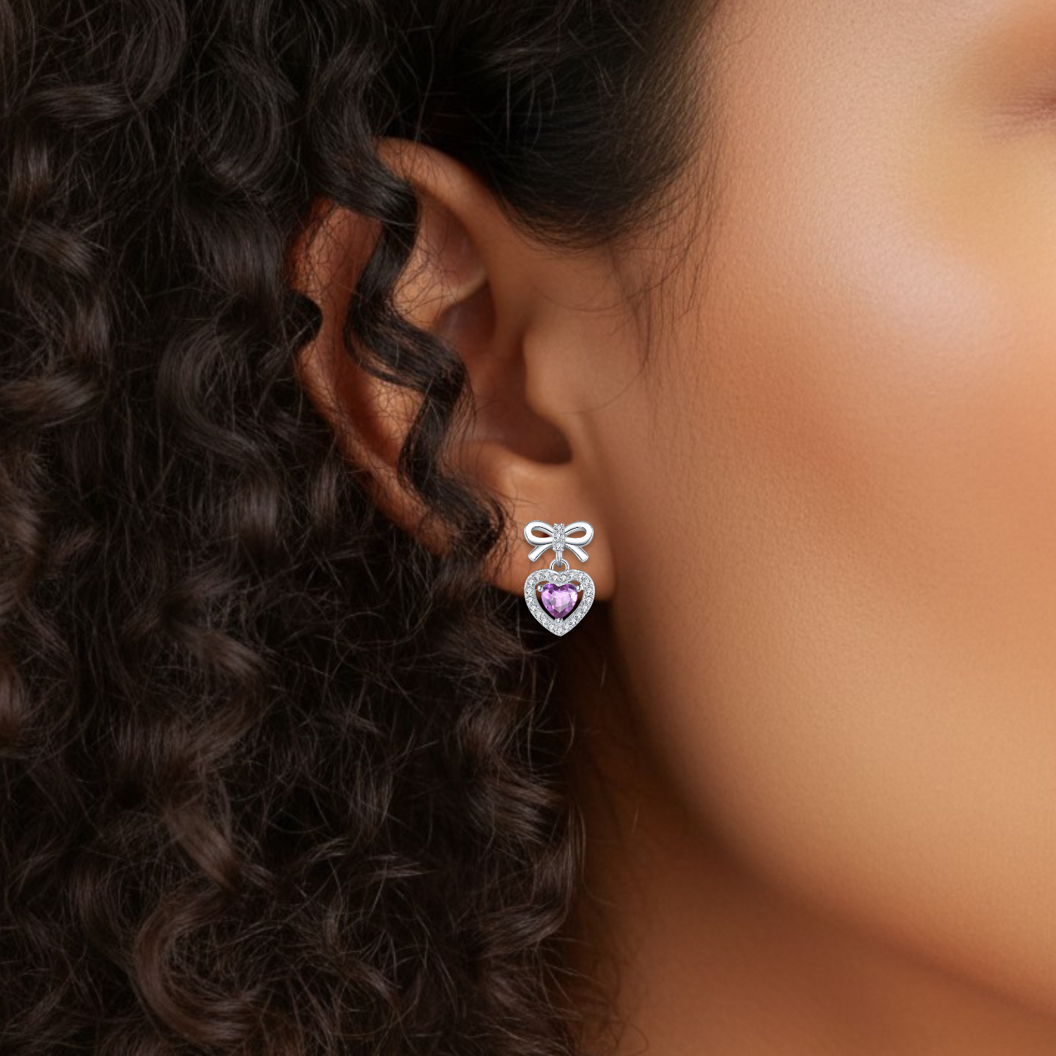 Close-up of an ear wearing a heart-shaped earring with a purple gemstone.