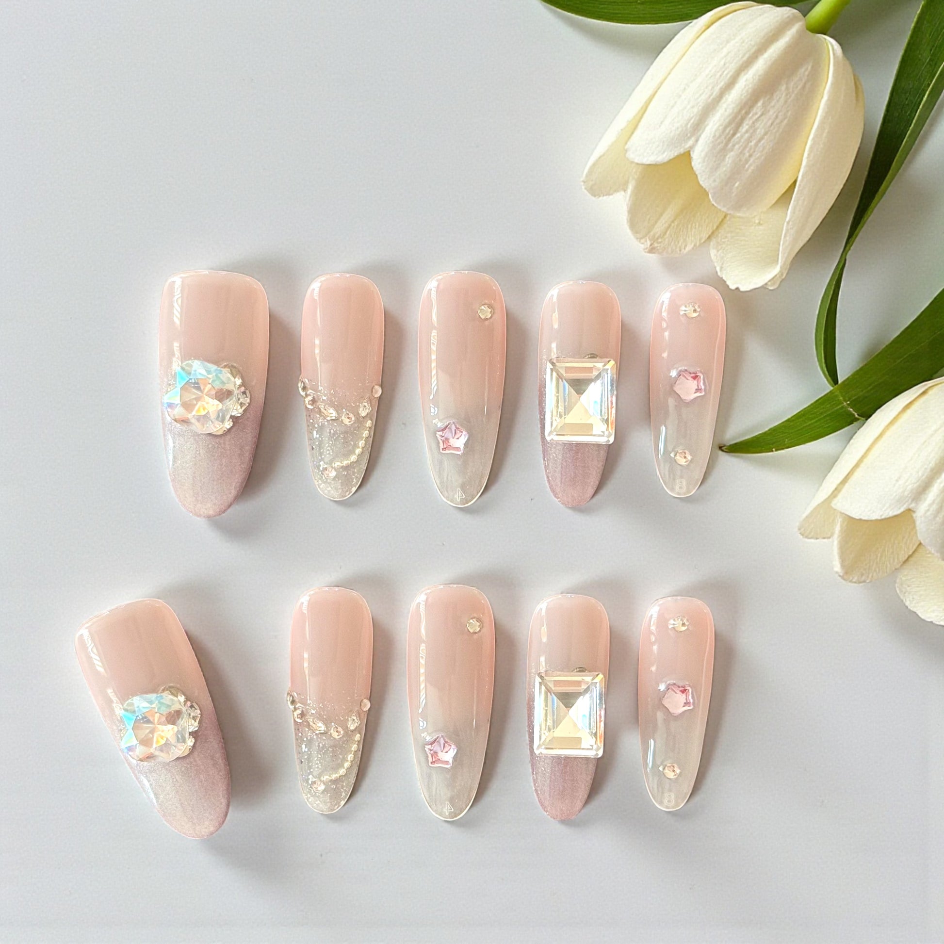Set of pink nail art with decorative elements on a white surface with tulips.