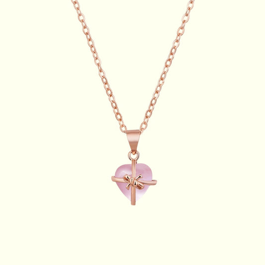 Rose gold necklace with a heart-shaped pink pendant on a white background