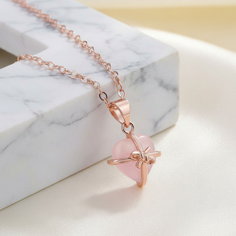 Rose gold necklace with a pink heart pendant on a marble surface