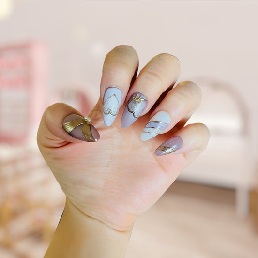 Hand with stylish nail art featuring butterflies and gold accents against a blurred background