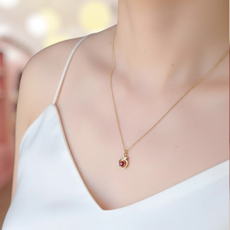 Gold necklace with a red gemstone on a blurred background