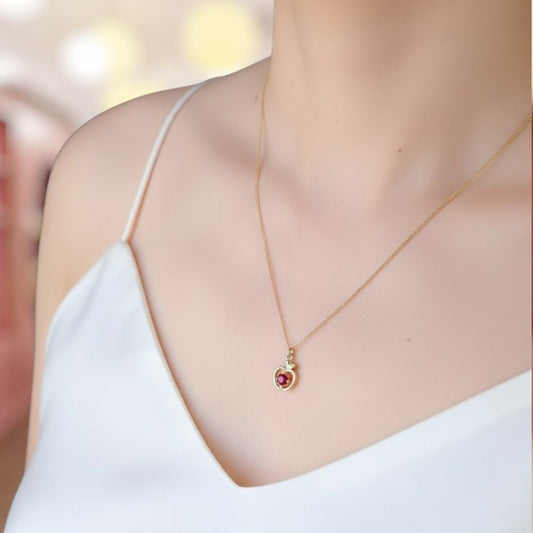 Gold necklace with a red gemstone on a blurred background