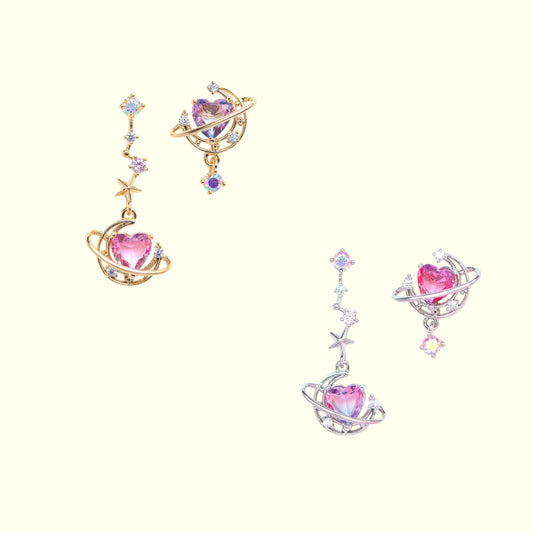 Pair of earrings with pink heart stones and gold and silver designs on a white background