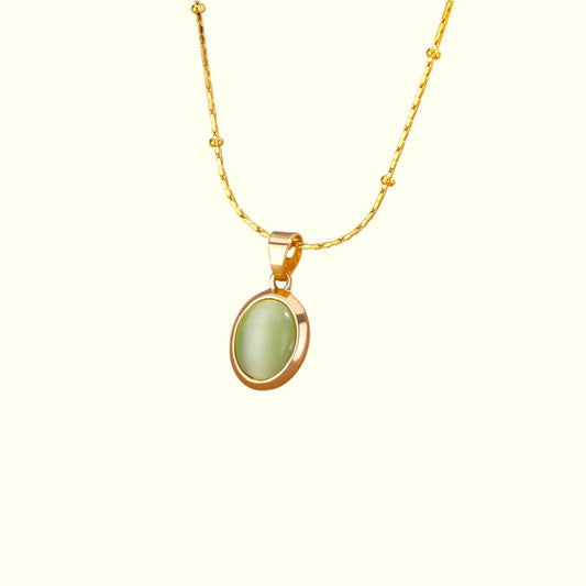 Gold necklace with a green pendant on a white background