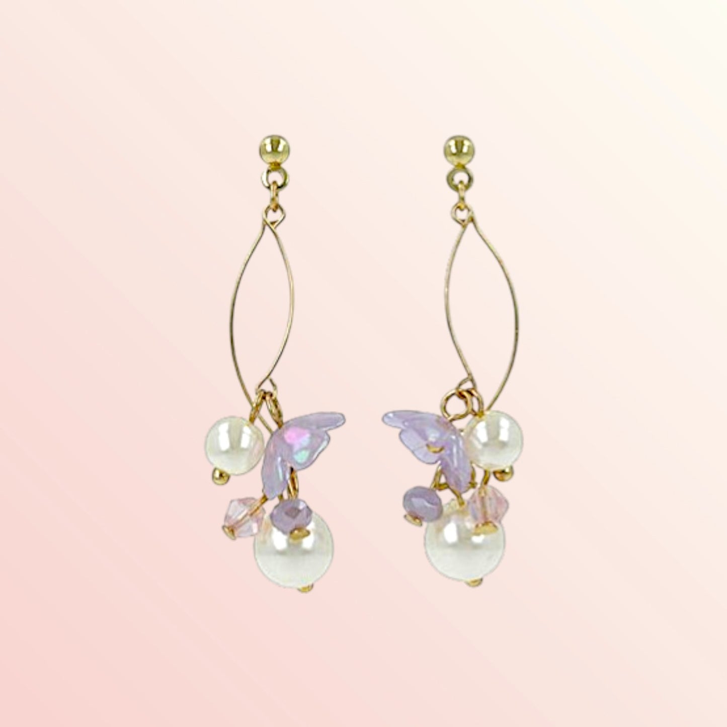 Gold earrings with pearl and purple accents on a pink background