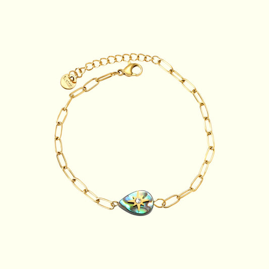 Gold bracelet with a heart-shaped gemstone on a white background