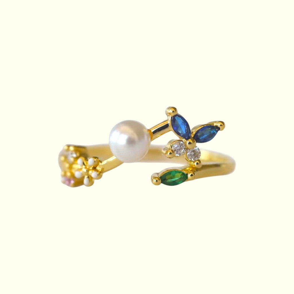 Gold ring with pearls and gemstones on a white background