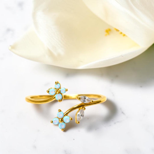 Gold ring with opal stones on a white surface