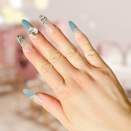 Hand with light blue and clear nail polish on a blurred background