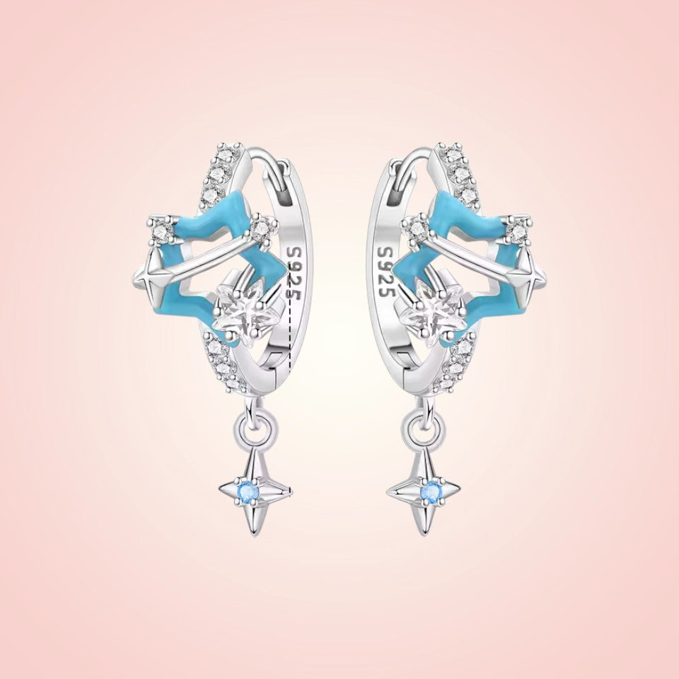 Star-shaped earrings with blue accents on a pink background