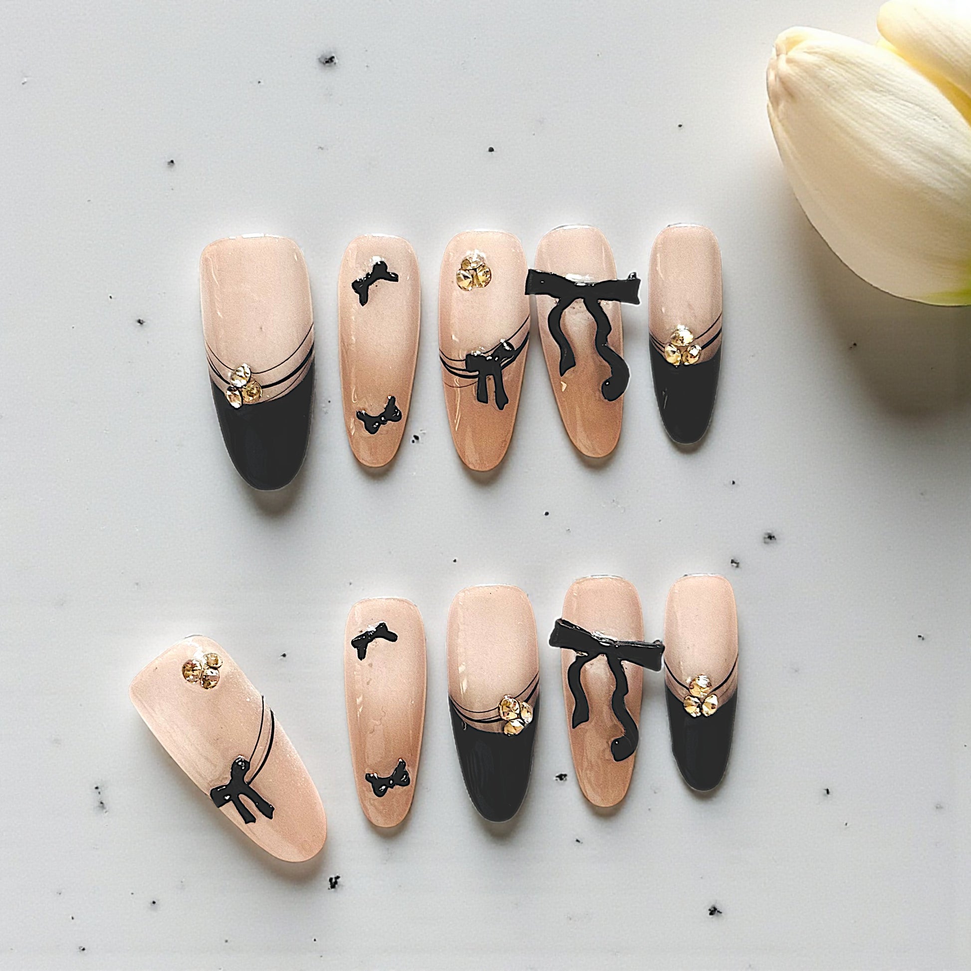 Nail art designs with bows and gold accents on a light background