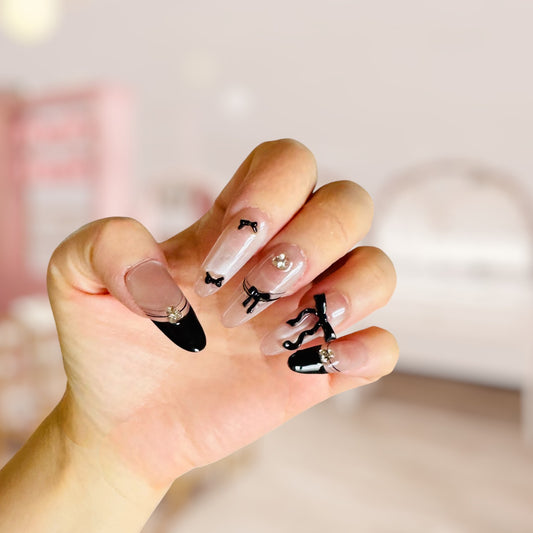 Hand with decorative nails featuring small figures and black tips on a blurred background