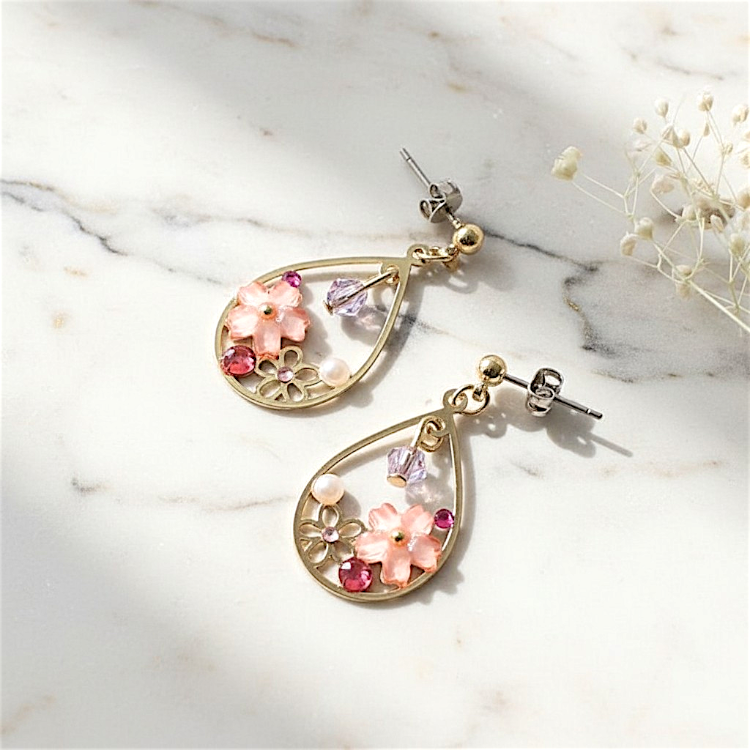 Gold earrings with floral designs on a marble surface