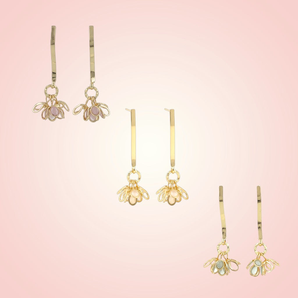 Set of gold bee-shaped earrings on a pink gradient background