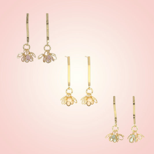 Set of gold bee-shaped earrings on a pink gradient background