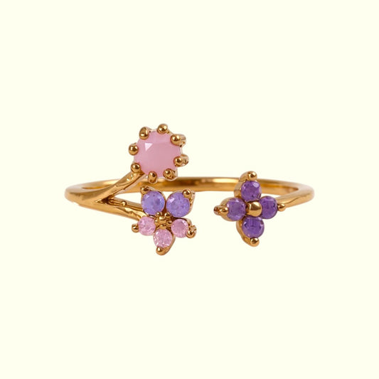 Gold ring with pink and purple gemstones on a white background