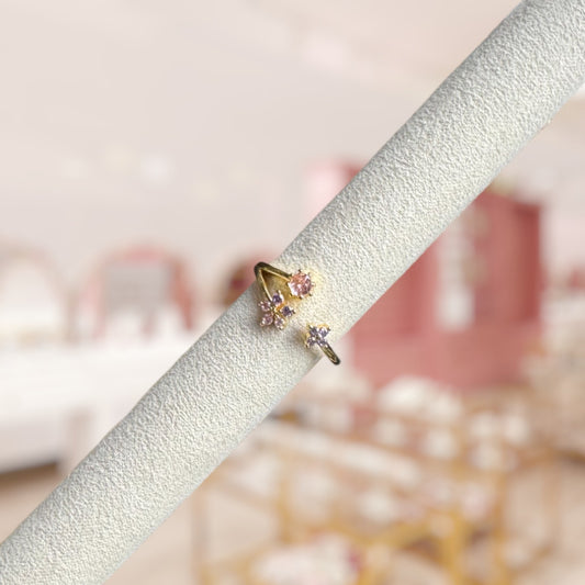 Gold ring with gemstones on a white stand against a blurred background