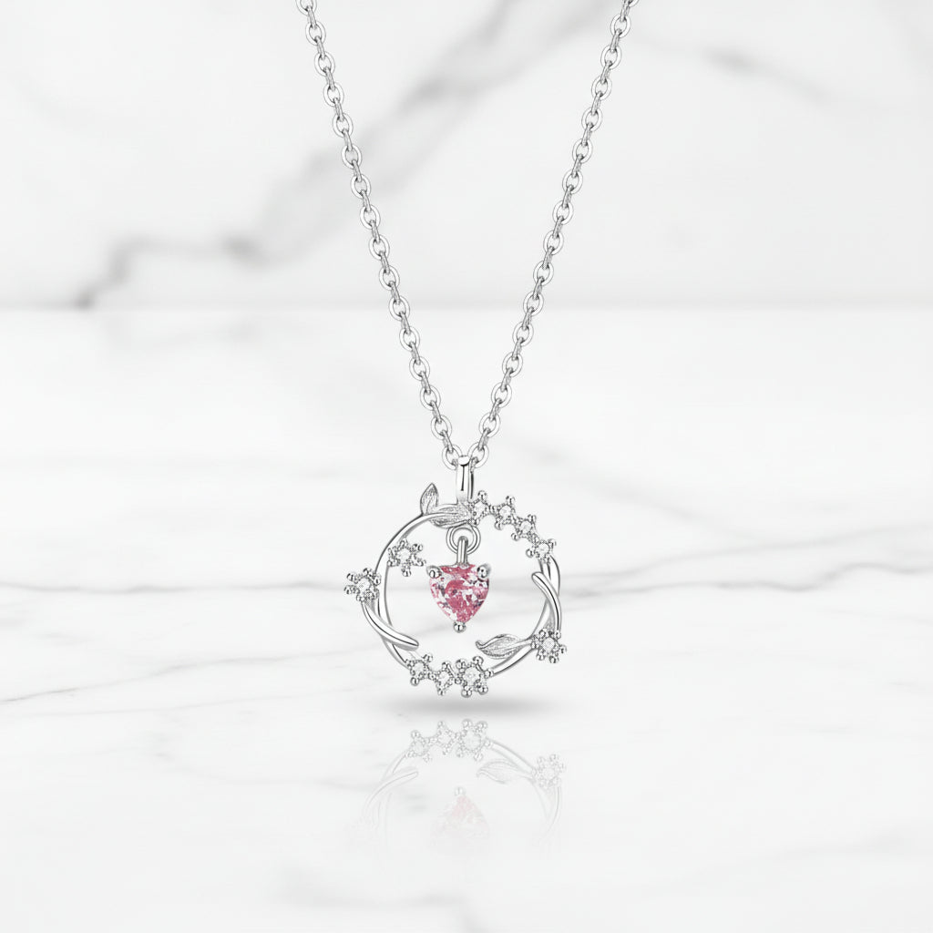 Silver necklace with a pink heart pendant on a white background