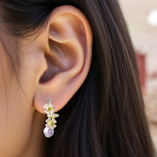 Close-up of an ear wearing a floral earring with a blurred background