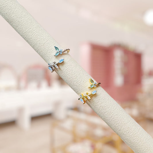 Small butterfly-shaped earrings on a beige rod with a blurred indoor background