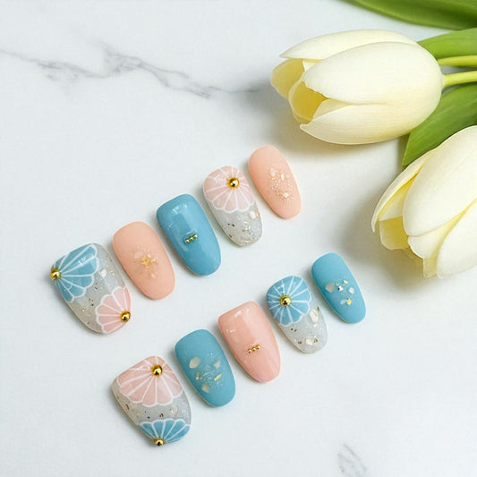 Pastel nail art with floral designs on a white surface with tulips.