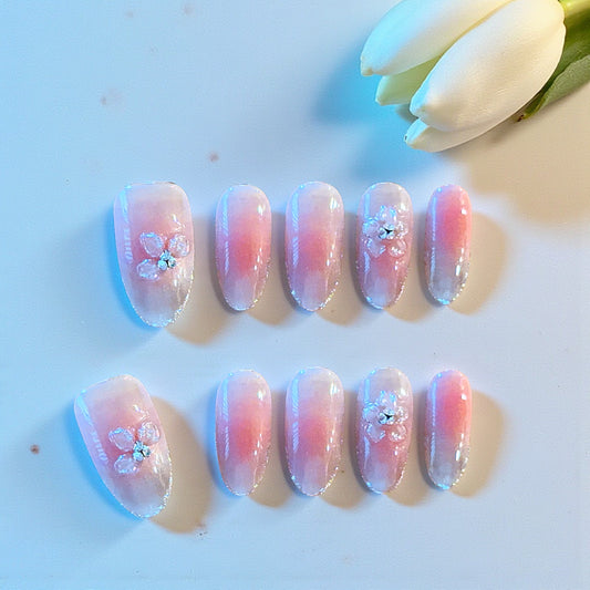 Set of pink and purple gradient nails with floral designs on a light background.