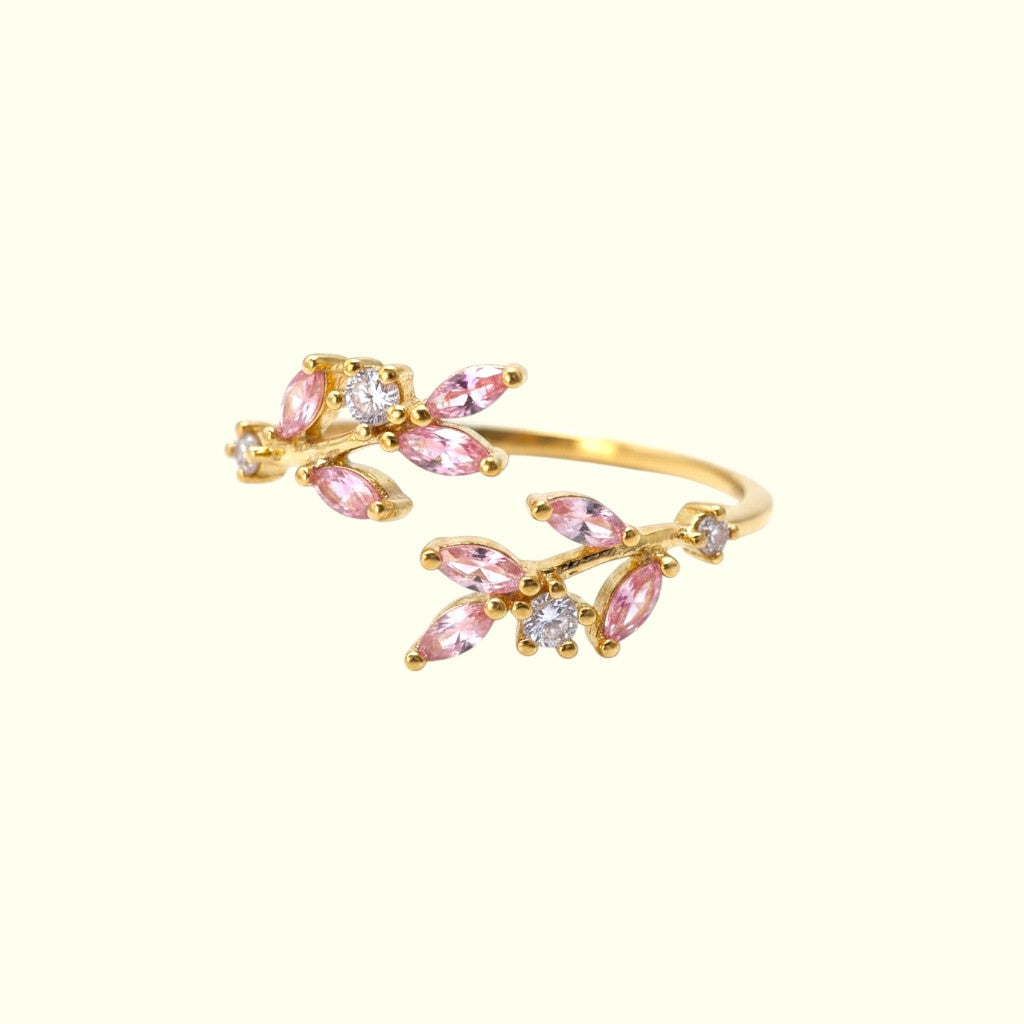 Gold ring with pink gemstones on a white background