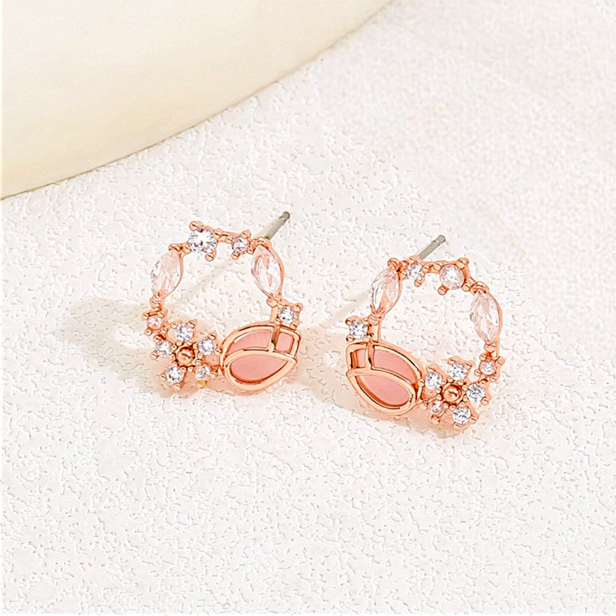 Rose gold hoop earrings with clear stones on a white background