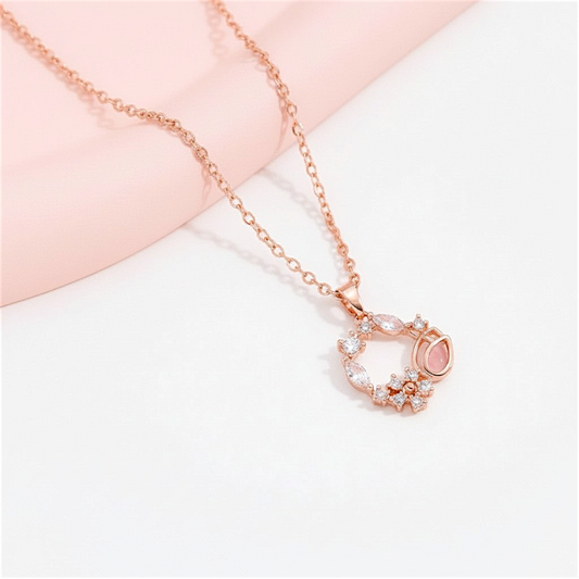Rose gold necklace with a heart-shaped pendant on a light pink background