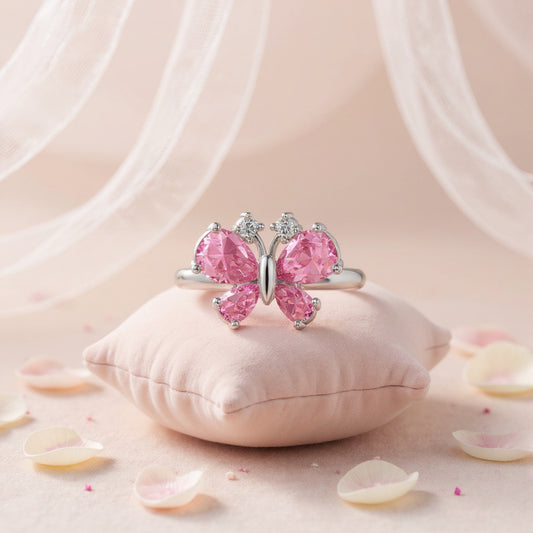 Butterfly-shaped ring with pink gemstones on a soft pink background
