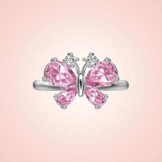 Butterfly-shaped ring with pink gemstones on a pink background