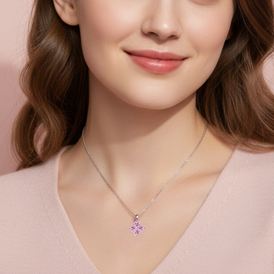 Woman wearing a necklace with a pink flower pendant against a soft pink background