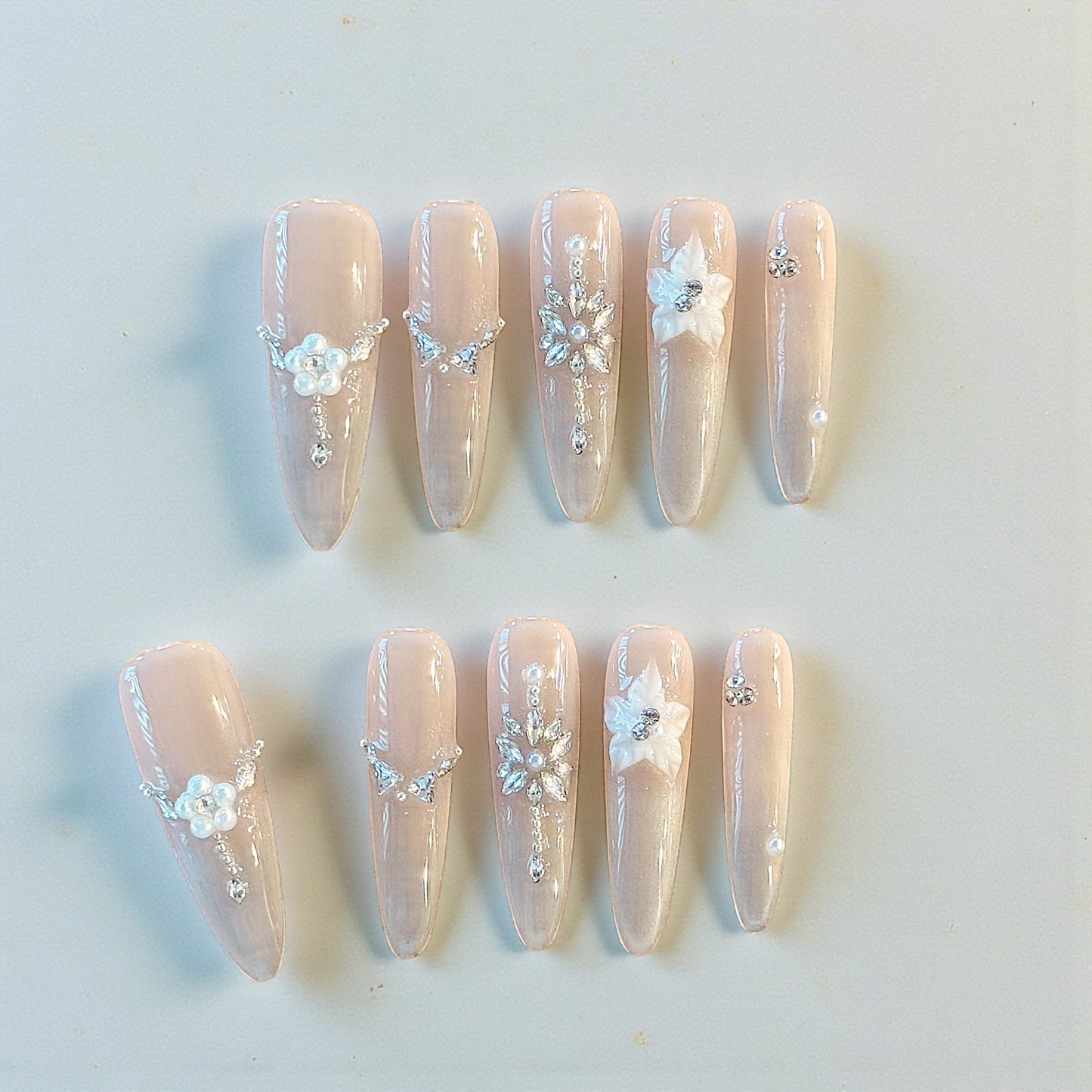 Set of decorative nails with floral and crystal designs on a light background