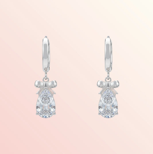 Pair of silver earrings with teardrop-shaped gemstones on a light pink background