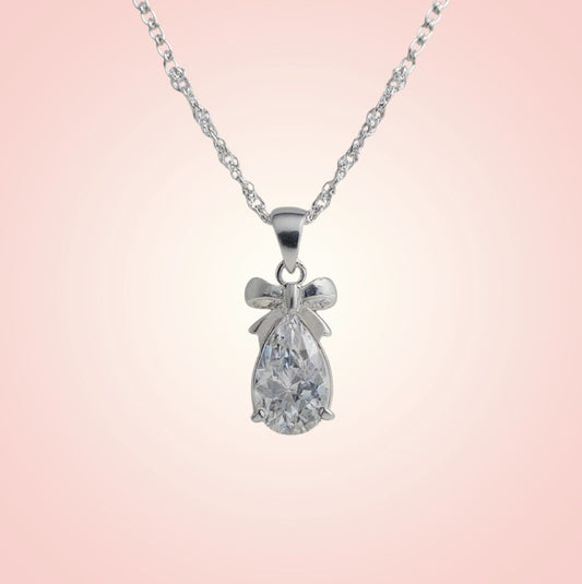 Silver necklace with a teardrop-shaped pendant on a pink background