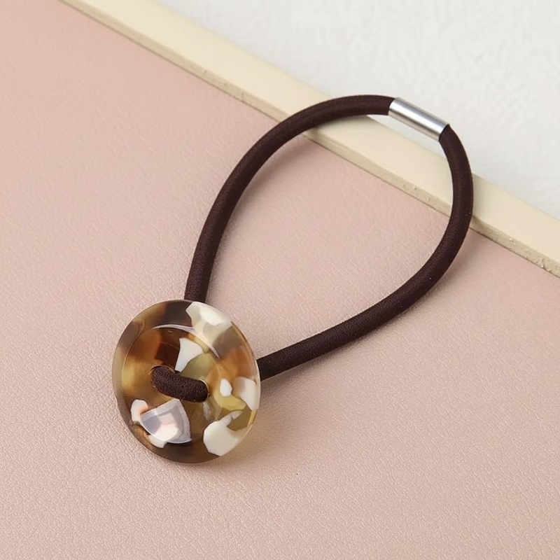 Hair tie with a decorative button on a pink surface