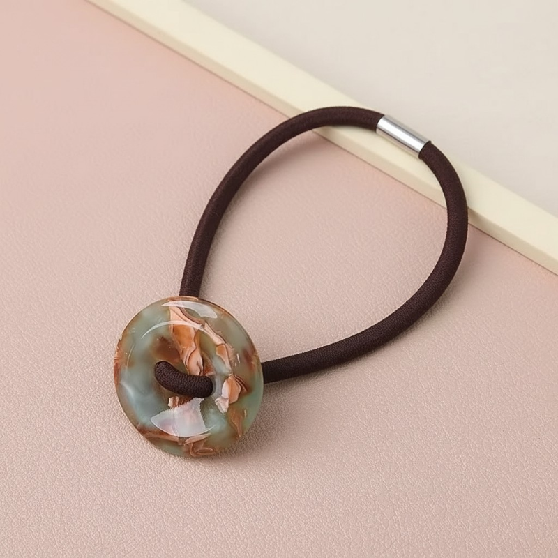 Hair elastic with a decorative button on a beige background