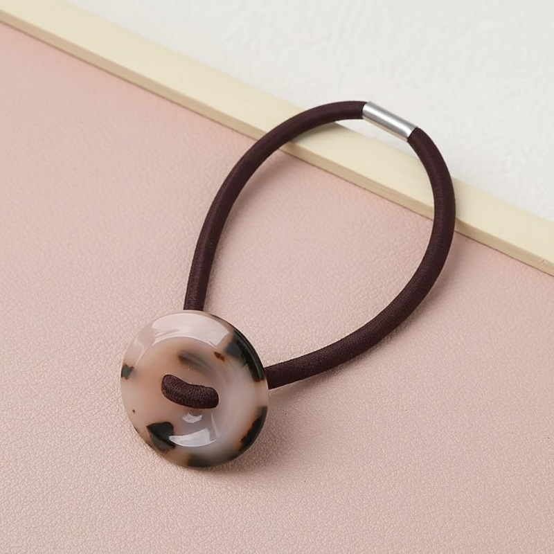 Hair tie with a marbled button on a pink surface