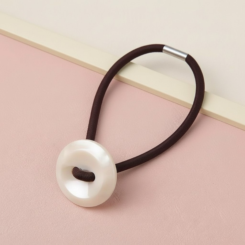 Hair tie with a large pearl-like bead on a pink and beige background