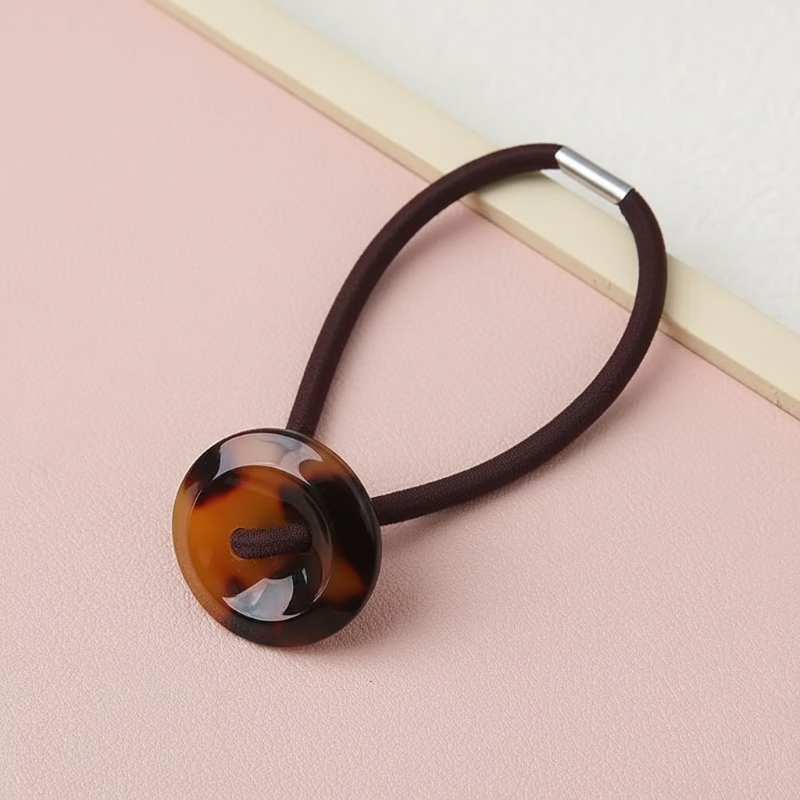 Hair tie with tortoiseshell button on a pink background