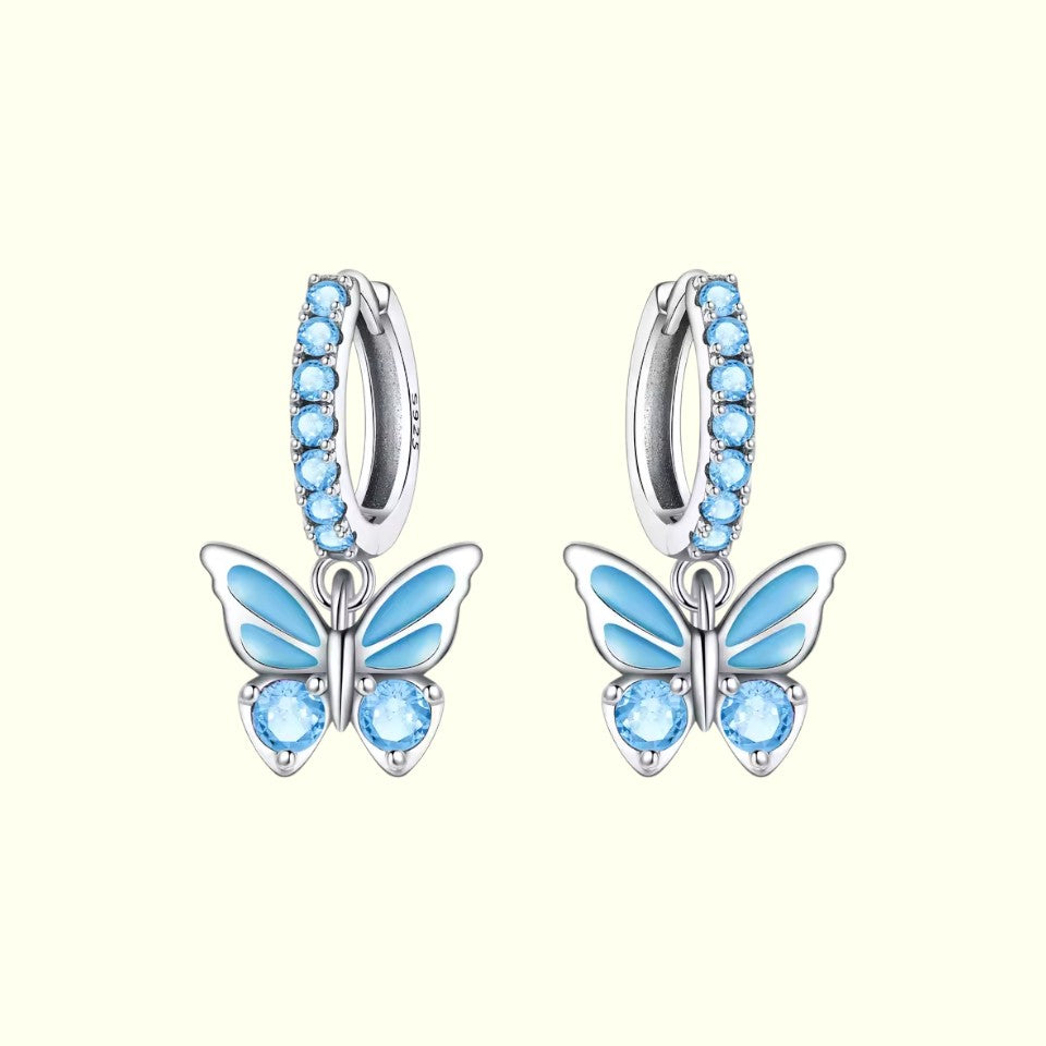 Butterfly earrings with blue gemstones on a white background