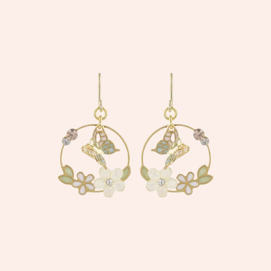 Gold hoop earrings with floral and butterfly designs on a light pink background