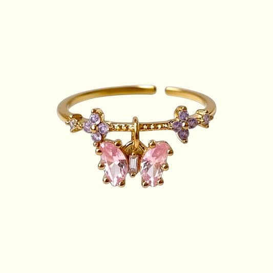 Gold open ring with pink and purple gemstones on a white background